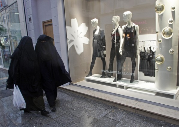 Mujeres con niqab pasan por delante de tiendas de moda, en Marsella, durante la última Nochebuena. JEAN-PAUL PELISSIER | REUTERS