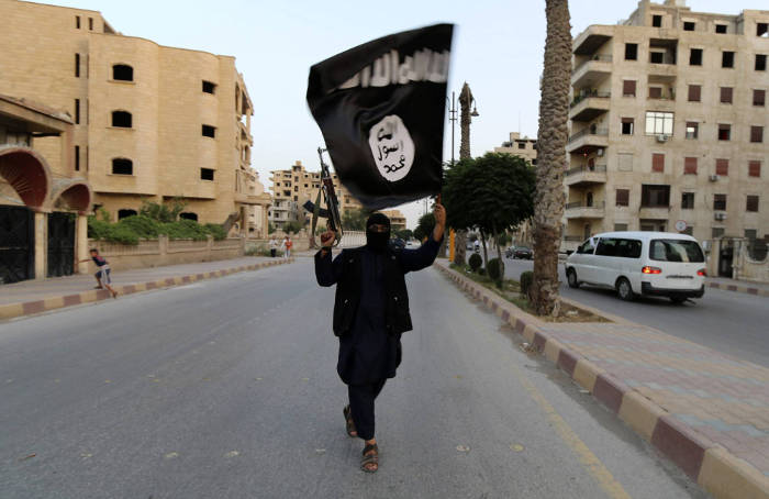 Persona levantando un arma y la bandera del Estado Islámico (archivo).EP