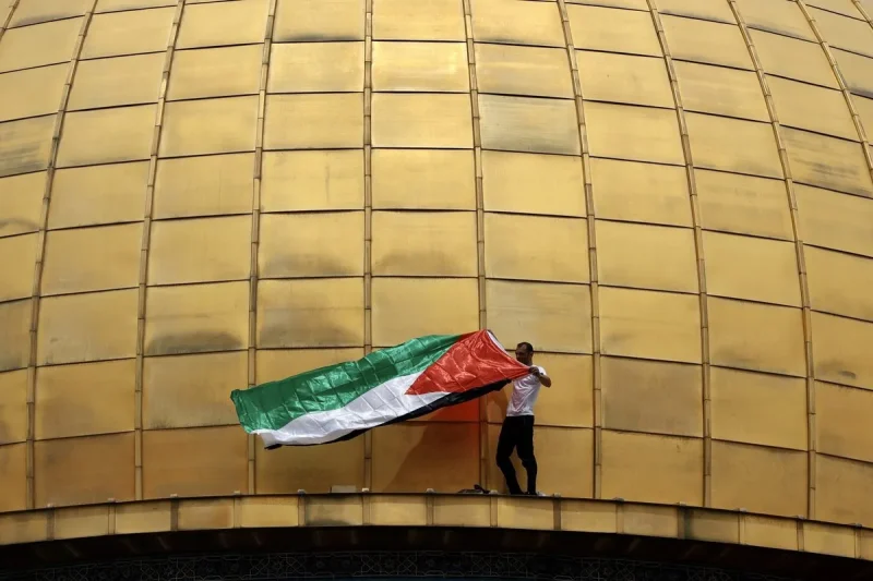 La bandera palestina se ve en la Cúpula de la Roca mientras la gente se reúne para la tercera oración del viernes de Ramadán en la mezquita de al-Aqsa en Jerusalén el 22 de abril de 2022
