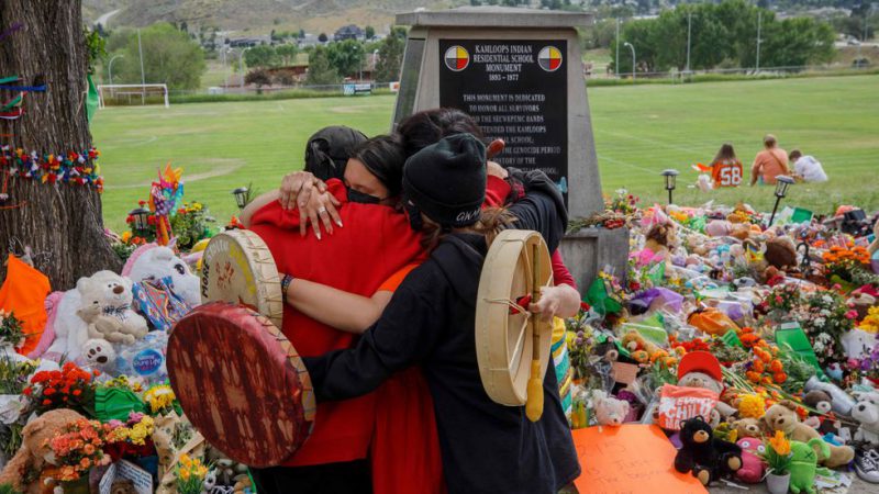 Miembros de la comunidad Mosakahiken Cree Nation se abrazan frente a un monumento en homenaje a las 215 tumbas de niños halladas en el antiguo internado Kamloops para indígenas en Columbia Británica.COLE BURSTON