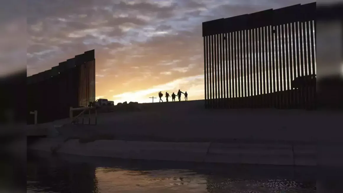 En esta foto de archivo del jueves 10 de junio de 2021, un par de familias de inmigrantes de Brasil caminan a través de un hueco en el muro fronterizo hacia Estados Unidos después de cruzar de México a Yuma, Arizona para buscar asilo.
