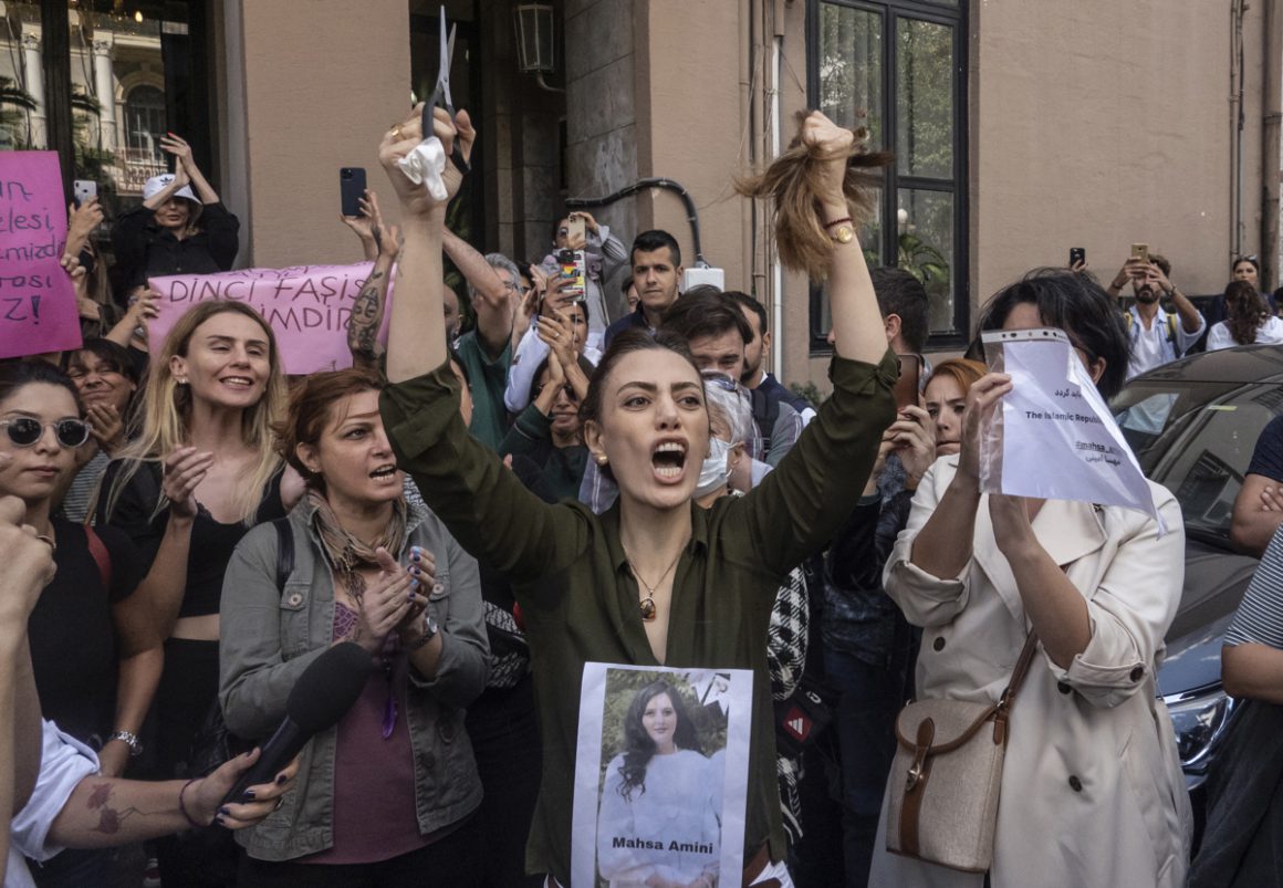 Una mujer iraní reacciona cortándose el pelo en una protesta frente a la embajada iraní en Estambul (Turquía), con una foto de Masha Amini en el pecho. — ERDEM SAHIN / EFE/EPA