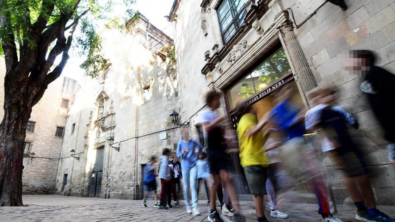 Alumnos salen por la puerta de la escuela Sant Felip Neri. A la izquierda, la iglesia, y más a la izquierda, la casa convento Xavier Jubierre