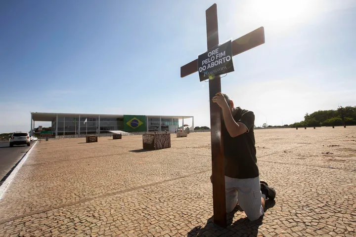 Un hombre mientras reza con una cruz, en la Plaza de los Tres poderes, en Brasília / Joedson Alves
