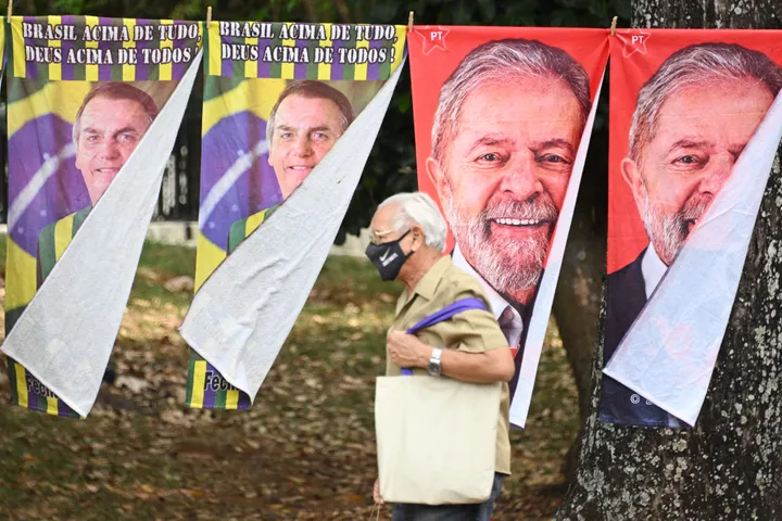 Un hombre cruza ante los carteles de Bolsonaro y Lula para las elecciones en Brasil.EVARISTO SA via Getty Images
