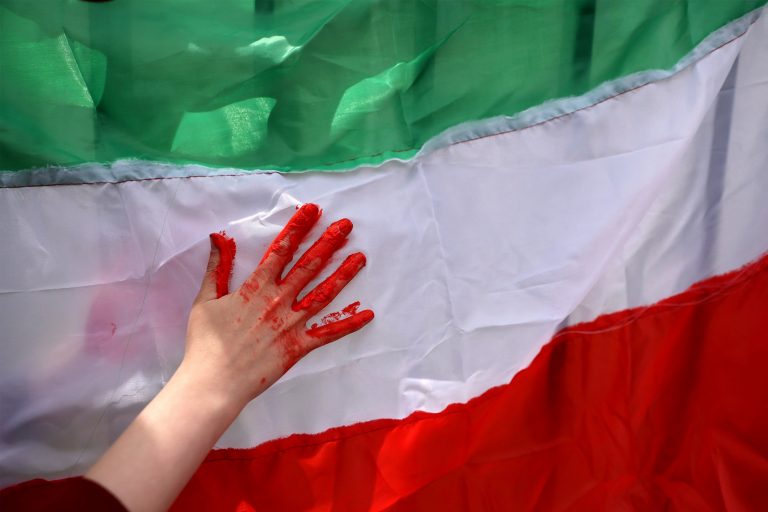 Una mujer usa pintura roja en una bandera iraní durante una protestan frente a la sede local de las Naciones Unidas en solidaridad con el pueblo iraní, en Santiago, Chile, a 11 de noviembre de 2022. -Foto: Ivan Alvarado