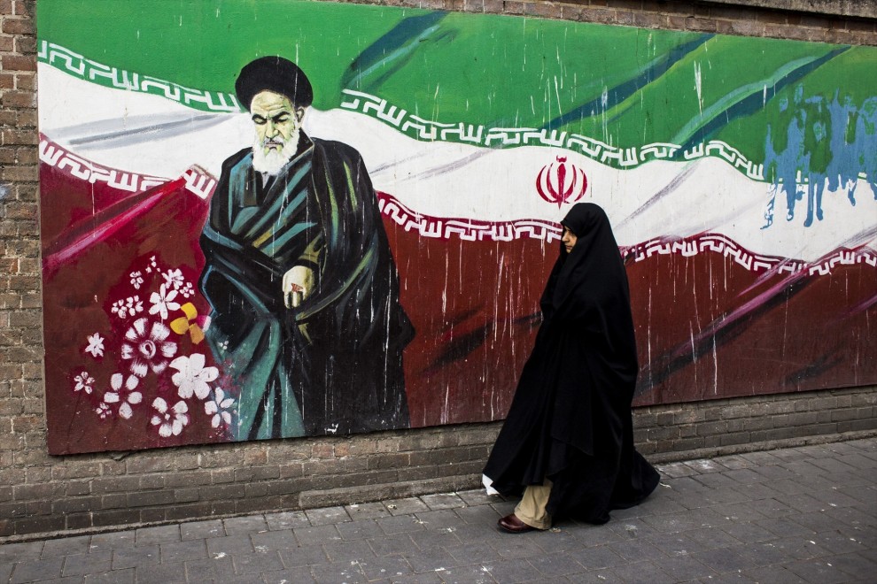Una mujer junto a un mural con la bandera iraní y el ayatolá Ruholá Jomeiní en Teherán (Irán). Imagen de Archivo. — DANI SALVÀ / VWPICS / ZUMA PRESS / CONTACTOPHOTO /