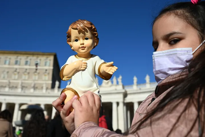 Una niña sostiene una imagen de Jesús la tradicional bendición papal de figurita, en la Plaza de San Pedro de Roma. VINCENZO PINTO via Getty Images
