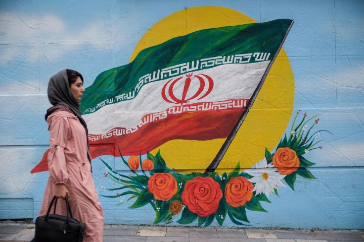 Una mujer camina frente a un mural con la bandera de Irán situado en una de las calles de TeheránROUZBEH FOULADI / ZUMA PRESS / CONTACTOPHOTO