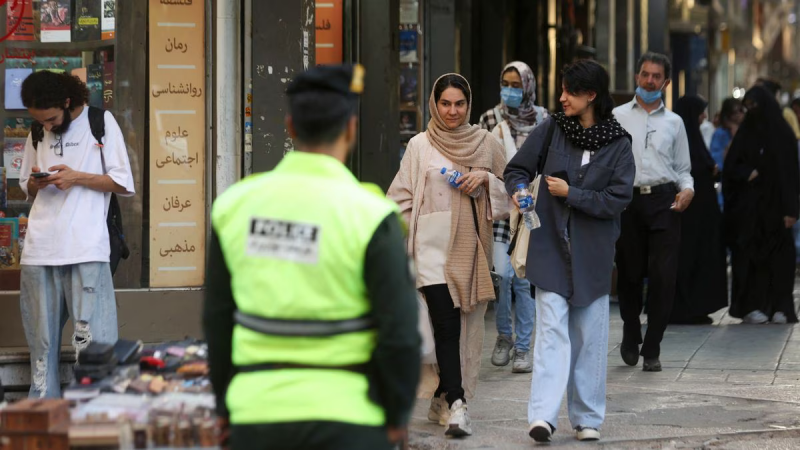 Varias mujeres, una de ellas sin velo, caminan cerca de un policía en Teherán el 16 de julio de 2023. Foto: WANA NEWS AGENCY (VIA REUTERS)