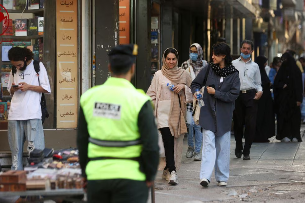 Mujeres pasean por una calle de Teherán en presencia de un policía.WANA NEWS AGENCY (via REUTERS)