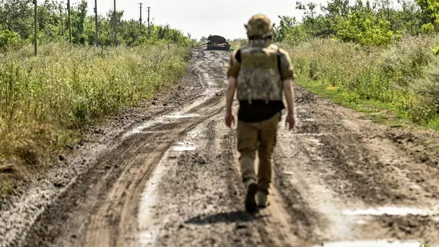 Un militar ucraniano por el camino de tierra mientras a lo lejos se ve un vehículo militar ruso destruido en el pueblo de Novodarivka, región de Zaporiyia, sureste de Ucrania. Dmytro Smolienko / Europa Press