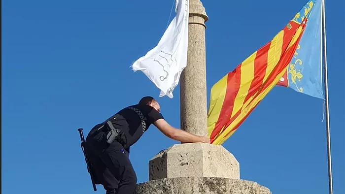 Un agente de policía sube a la torre a retirar la bandera.@epcvalenciana