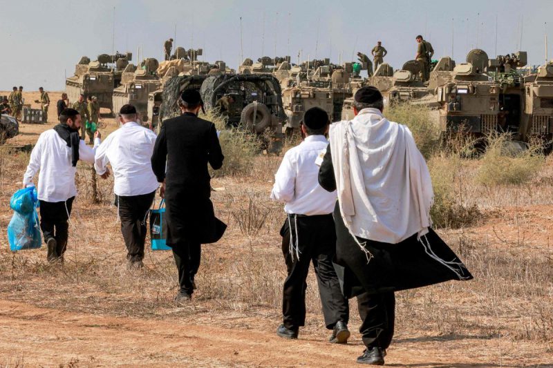 Un grupo de judíos ultraortodoxos visitan a soldados israelíes en la frontera con Gaza, el pasado 11 de octubre. / MENAHEM KAHANA / AFP