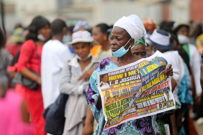 Una mujer porta un periódico en Nigeria que da cuenta de la muerte, en 2021, del evangelista TB Joshua. / AKINTUNDE AKINLEYE / EFE
