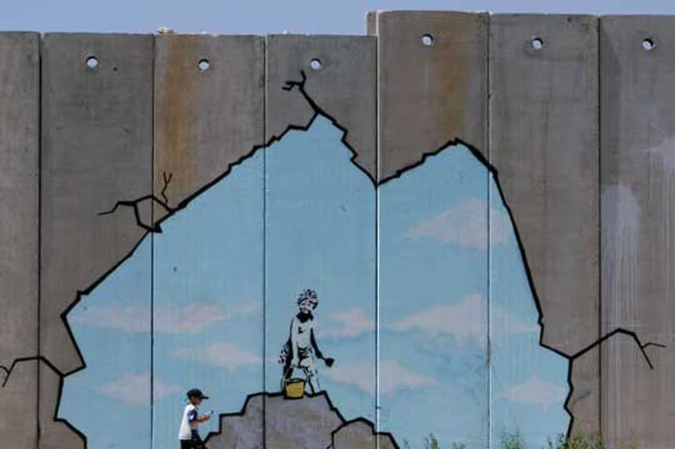 Un niño palestino pasa junto a una de las pinturas del muro de Gaza.REUTERS