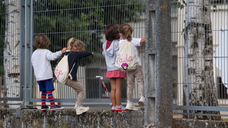Varios niños y niñas se encaraman a la valla del CEIP Manuel Mallo de Nadela, en Nadela, Lugo. EP