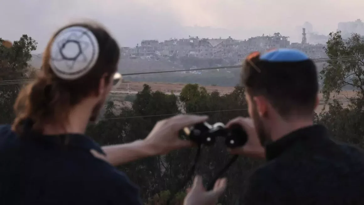 Dos judíos ultraortodoxos observan una zona de Gaza bombardeada desde el sur de Israel. / Jack Guez / AFP