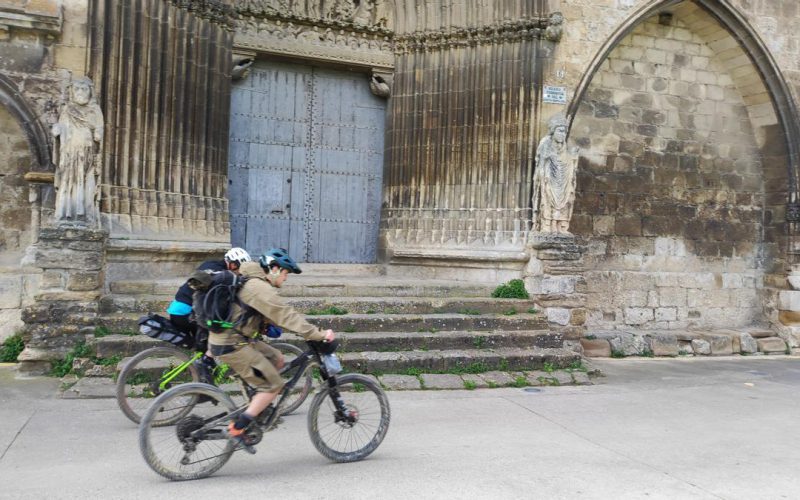 Dos peregrinos en bicicleta pasan por delante de la portada del Santo Sepulcro en Estella-Lizarra Javier Arizaleta