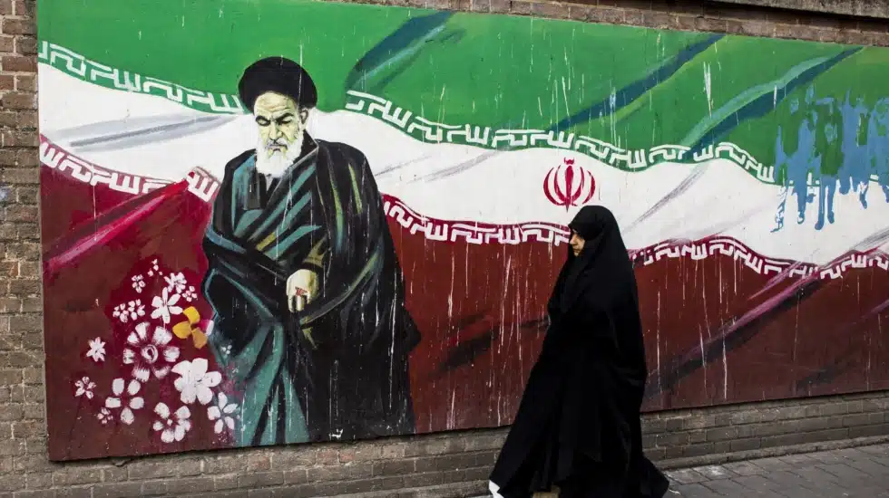 Una mujer junto a un mural con la bandera iraní y el ayatolá Ruholá Jomeini en Teherán. EP
