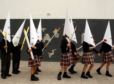 Unos niños, vestidos de penitentes, representan una procesión en un colegio de Sevilla, poco antes del inicio de las vacaciones de Semana Santa, en 2023.MARCELO DEL POZO (REUTERS)