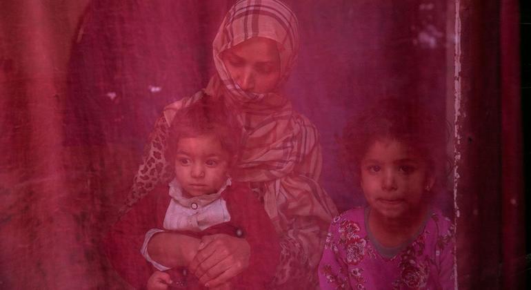© ONU MUJERES/Sayed Habib Bidell. Ahora en paro, una mujer se sienta en casa con sus dos hijas.