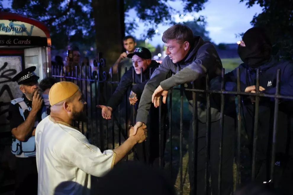 Un miembro de la mezquita Abdullah Quilliam estrecha la mano de un manifestante durante una manifestación en la mezquita Abdullah Quilliam en Liverpool, Gran Bretaña, el 02 de agosto de 2024. — EFE/EPA/ADAM VAUGHAN