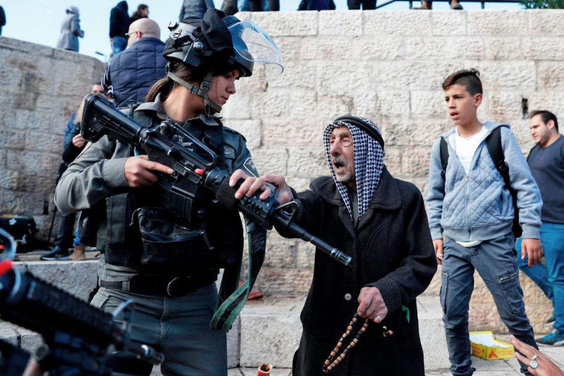 Una soldado israelí sostiene su arma ante un anciano palestino. Foto: StoptheWall