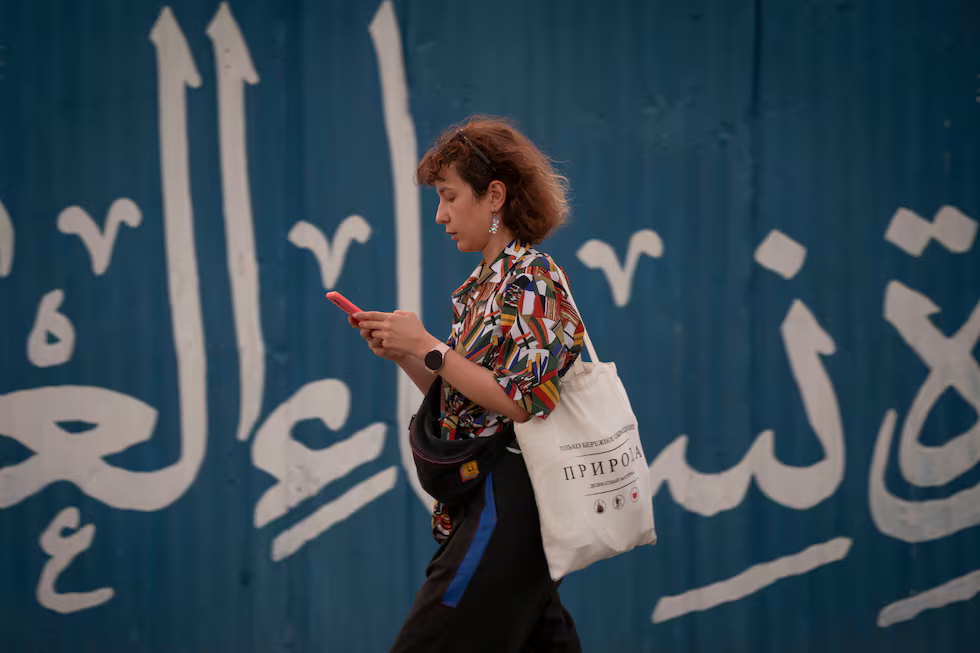 Una mujer consulta su móvil mientras camina sin velo por Teherán, el 30 de junio.NurPhoto (NurPhoto via Getty Images)