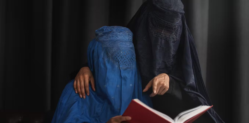 Mujeres afganas musulmanas vestidas con el burka leen el Corán. Shutterstock