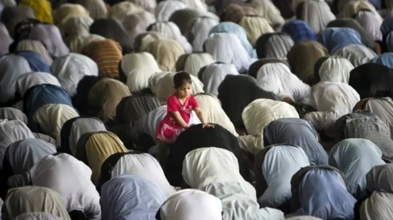 Una niña intenta jugar con su padre mientras que éste reza en un templo islámico.Morteza Nikoubazl / REUTERS