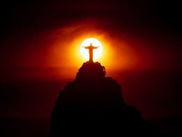 El Cristo Redentor de Río de Janeiro con el sol del atardecer centrado tras el monumento