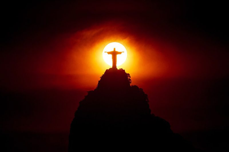 El Cristo Redentor de Río de Janeiro con el sol del atardecer centrado tras el monumento